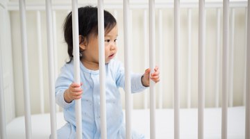 Toddler boy (18-21 months)  climbing out of crib, rear view