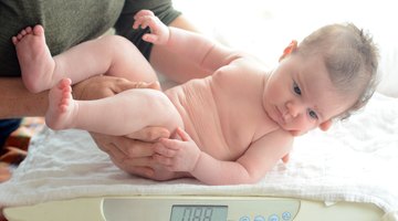 Baby (3-6 months) lying on white sheets, close-up