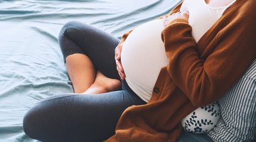 Pregnant woman at work with laptop looking stressed