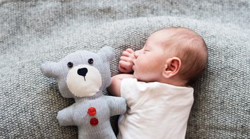 Beautiful pregnant woman sitting at bed and holds hands on belly in bedroom at home.