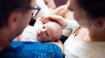 Female baby (6-9 months) crawling towards camera as another baby playing behind