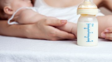 Mother Holding Newborn Baby Daughter At Kitchen Table