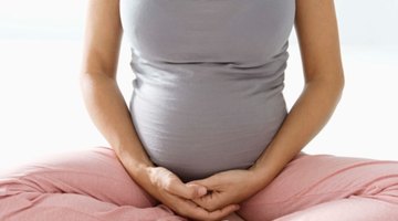Smiling pregnant woman on bed with her hand at belly