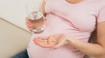 Pregnant woman taking pill against heartburn