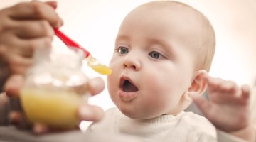 Cute baby with milk bottle sitting on bed