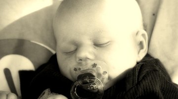 woman talking on the telephone and looking at thermometer while boy (10-12) sleeps in bed