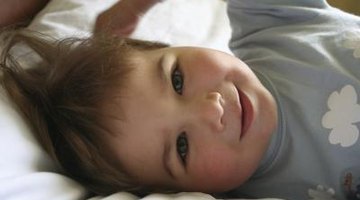 Child playing with blanket on bed