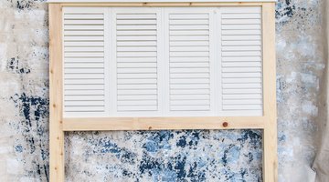 The headboard displays reclaimed shutters, framed with new lumber, and finished with crown molding at the top