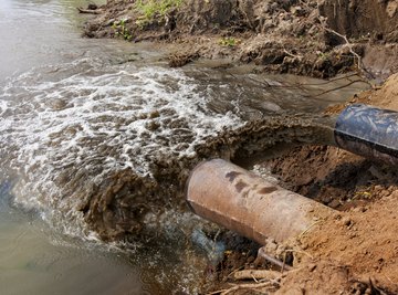 Industrial waste polluting a river through a pipe.