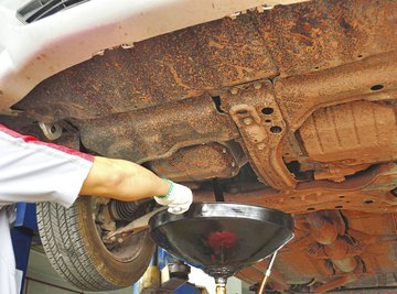 A mechanic changes a cars oil.