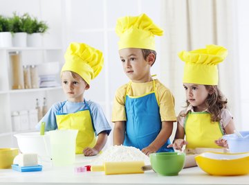 Group of young students dressed in cooking gear in classroom.