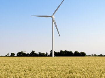 A wind turbine spins in the middle of a wheat field.