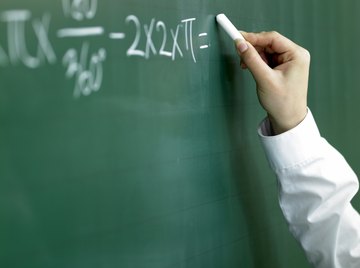 Close-up of student writing math problem on chalkboard.