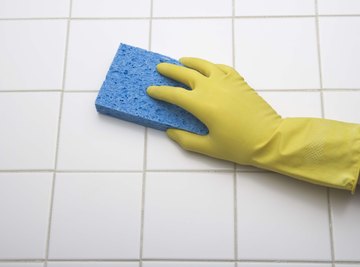 A gloved hand is cleaning the kitchen floor.