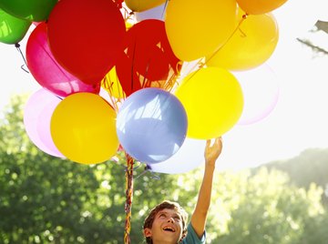 A boy holding balloons filled with helium.