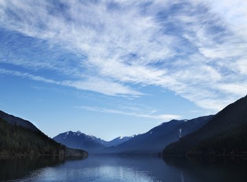 Clouds in the blue sky hovering over a lake in the mountains.