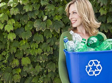 A woman is holding a recycling bin.