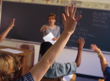 Students raising their hands to participate in a classroom discussion.