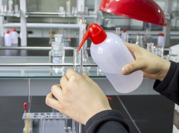 Close-up of a student in a chemistry lab pouring water into a test tube