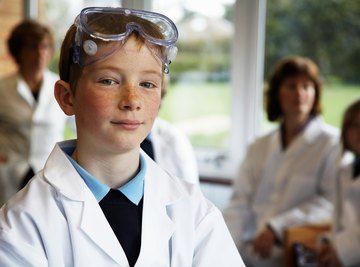 Young boy with lab coat and goggles in science class.