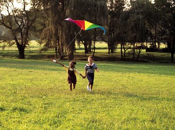 Two girls flying a kite in a field.