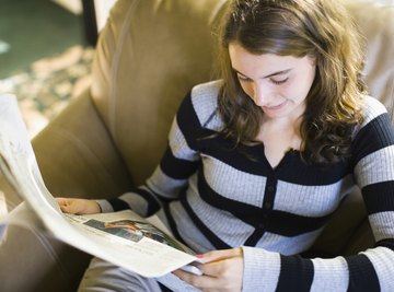 Teenage girl reading a newspaper.