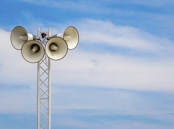 A tower with loudspeakers against a summer sky.
