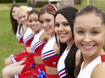 Smiling cheerleaders sitting on bench.