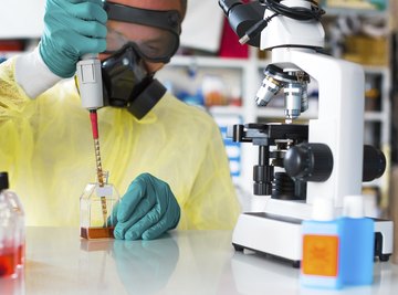 Scientist wearing protective gear uses micropipette in lab