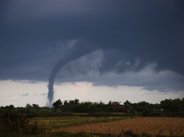 A tornado forms and moves across the ground in the distance.