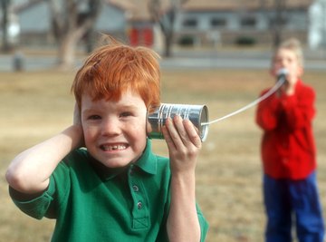 Two boys using cans and string as walkie-talkies