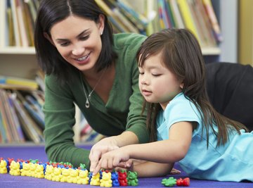 Teacher helping student count figurines in classroom.