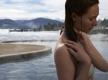 A woman stepping out of a hot spring in the mountains.
