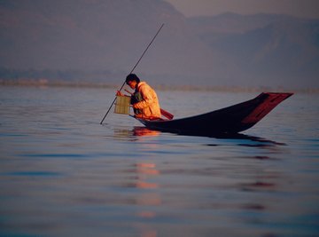 Silhouette of man spear fishing off small boat