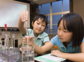 Two kids playing with laboratory gear like beakers and test tubes.