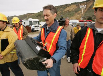 A team using equipment to test the geographical compostion of a hillside.