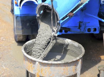 Wet cement pours out of a cement trunk mixer into a barrel