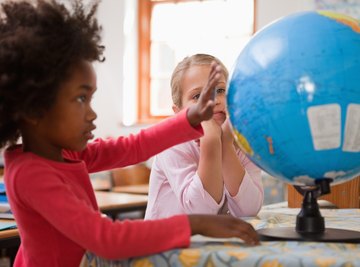 Two students looking at a globe on a table in the classroom.