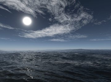 A moon rises over an ocean.