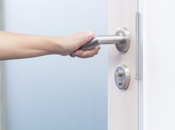 A woman grabs a door handle.