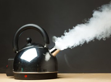 Tea kettle with boiling water on a black background, Stock image