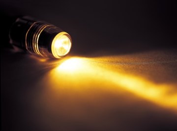The flow of electrons from zinc to copper produces enough current to power a small flashlight bulb.