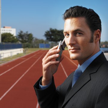 businessman on running track talking on mobile phone, portrait