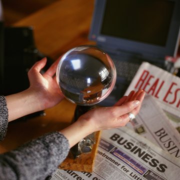 Woman's cupping crystal ball resting on newspapers