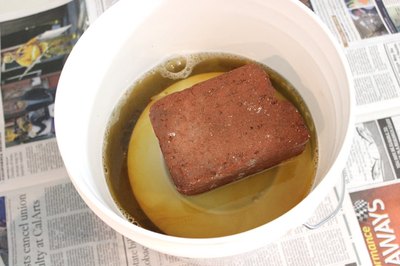 A plate and brick keep the pine cones submerged.