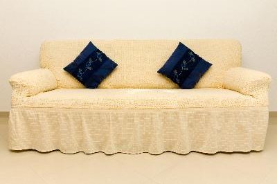 Beige couch and blue cushions. image by juri semjonow from Fotolia.com Don't let your dog jump on and off the couch.