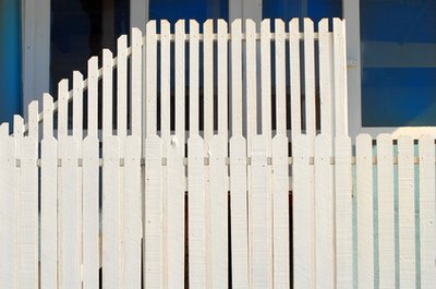 two tiered white picket fence in front of a blue building image by David Smith from Fotolia.com Picket fencing sections can be installed temporarily using freestanding posts.