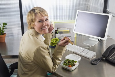 Creatas Images/Creatas/Getty Images Eating at the desk is a very common practice at most companies.