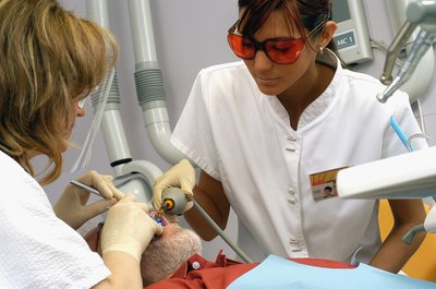 Medioimages/Photodisc/Photodisc/Getty Images Dental assistants gives instruments to the dentist as needed during procedures