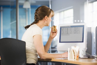 BananaStock/BananaStock/Getty Images Eating lunch at your desk will lower your productivity and increase your waistline.